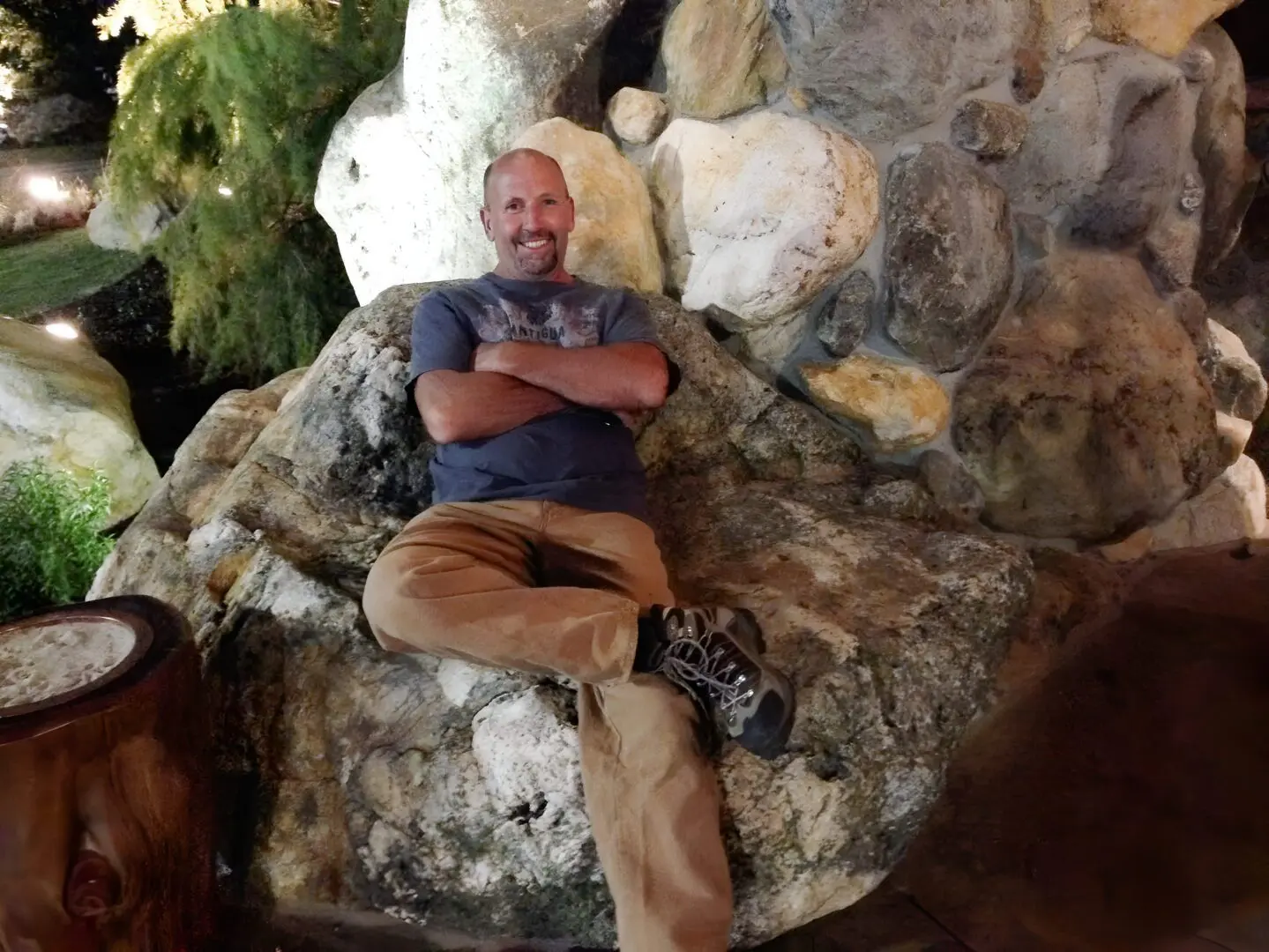 Man sitting on rock, smiling at night.